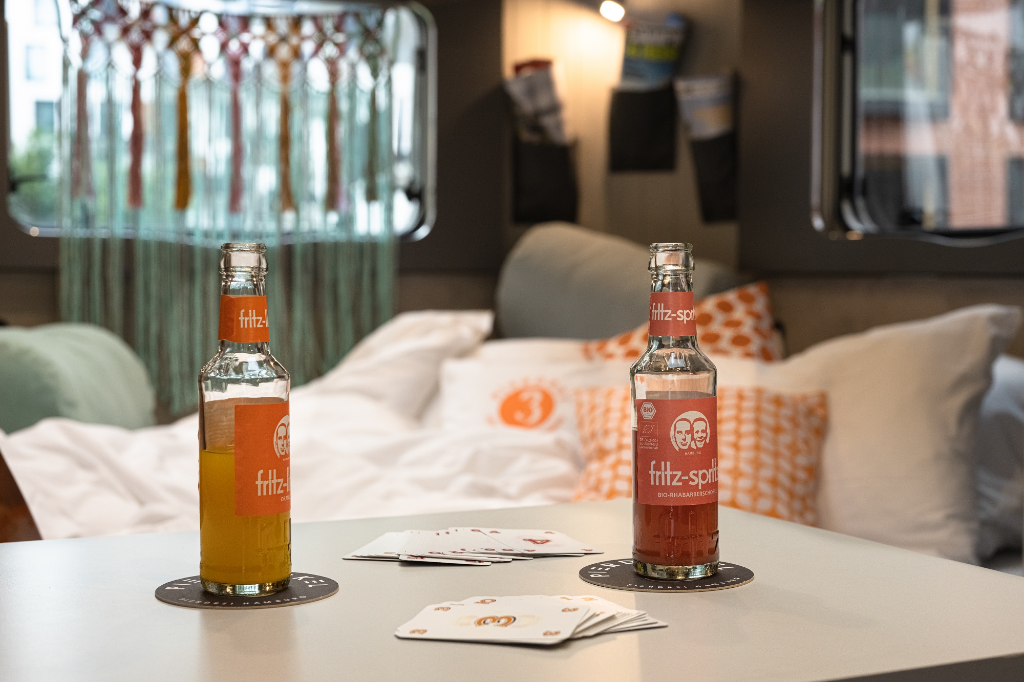 View on two Fritz drinks in Camper Flower Coco with bed and window in the background