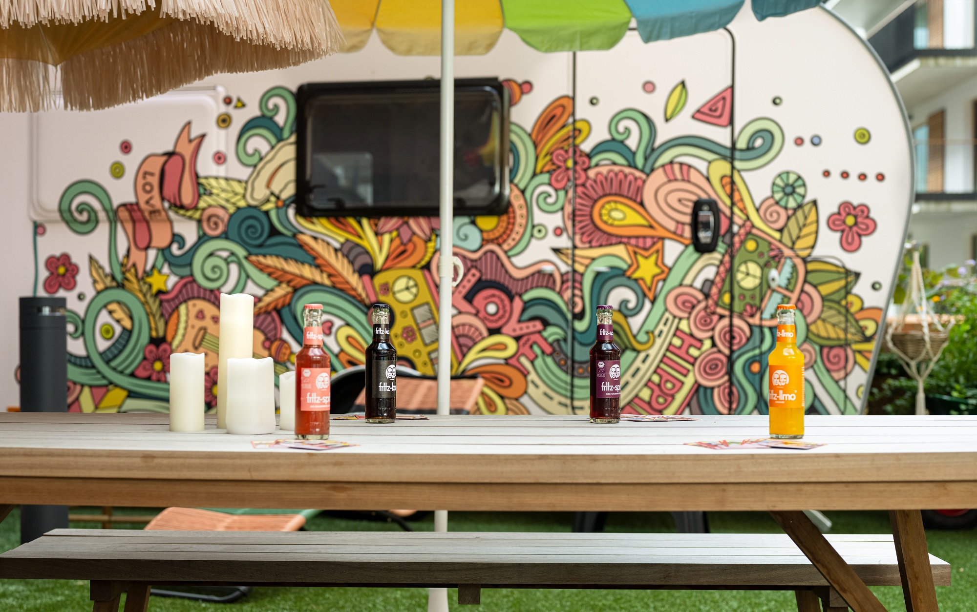 Detailaufnahme einer Holzbank mit bunten HIPPIE Camper 