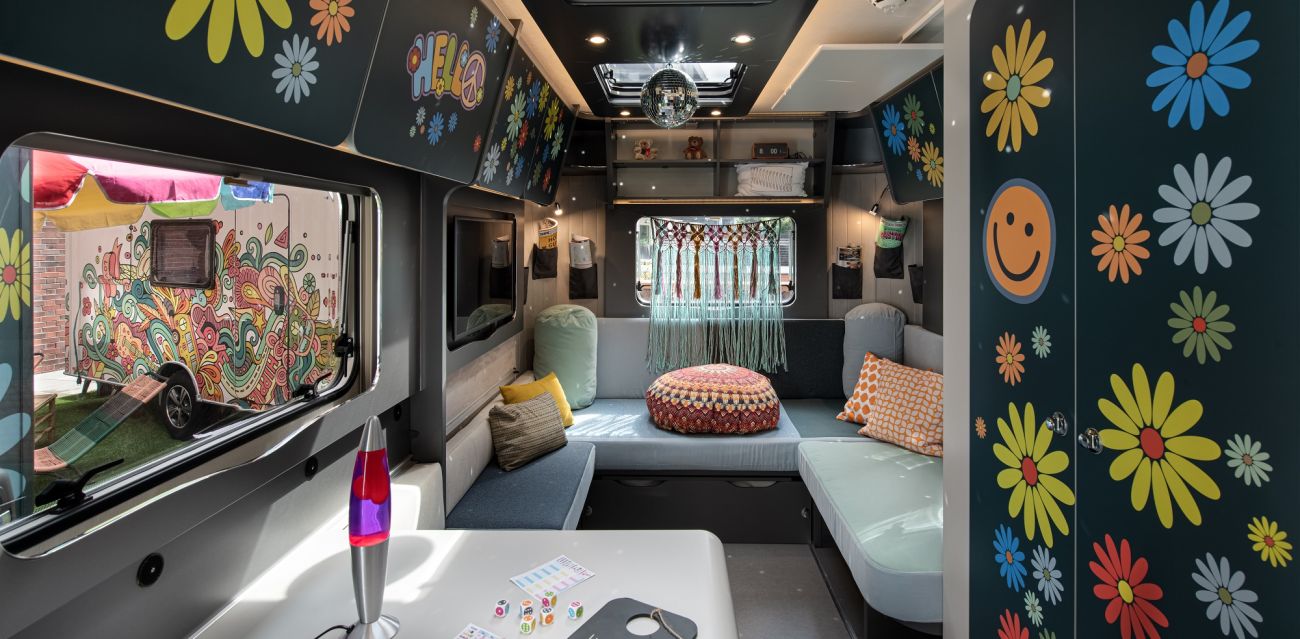 View of table and chill lounge in floral designed camper FLOWER Coco